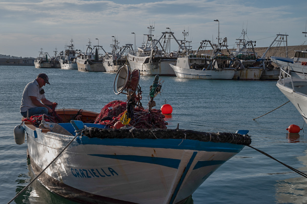 Vieste, un pescatore sistema la rete nel porto del paese