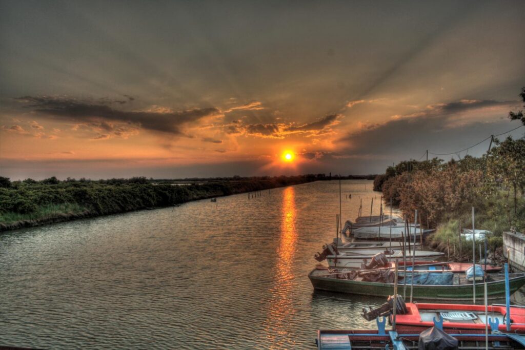 Tramonto sulla laguna di Marano, con le barche dei pescatori lungo il canale