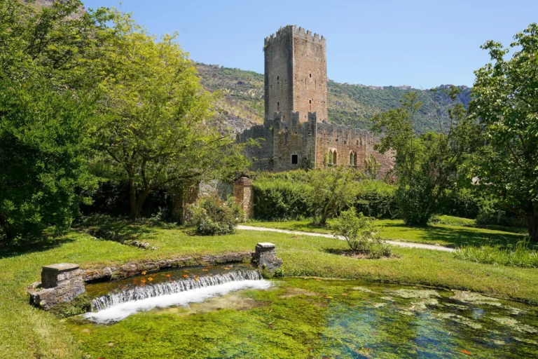La torre del castello di Ninfa sopra il giardino e il fiume