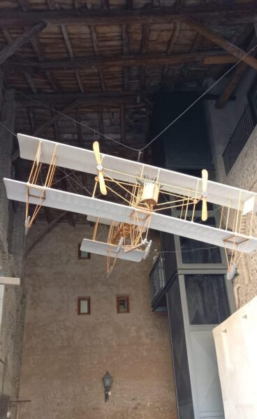 Modellino di un biplano d'epoca appeso sotto il soffitto in legno di un portico, lungo il cammino