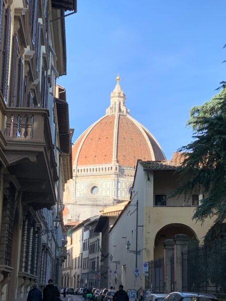 La cupola del Brunelleschi e il Duomo di Firenze in fondo a una via del centro