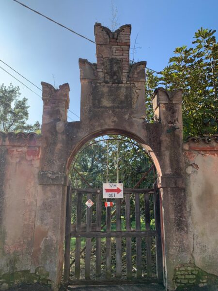 Antico portale merlato con la freccia della Via degli Dei, all'inizio del percorso lungo il Reno
