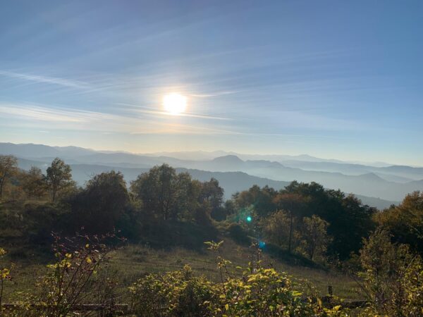 Il sole basso sulle valli dell'Appennino velate di foschia