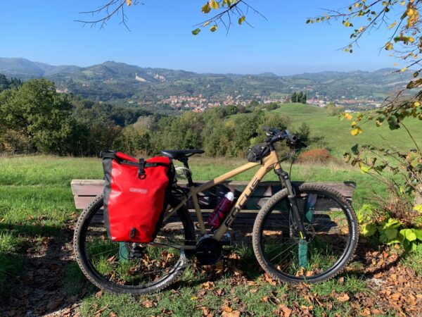 Bicicletta accanto a una panchina con vista su un paese della valle e sulle colline dell'Appennino